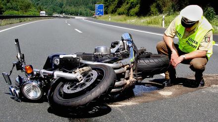 Ein Polizist begutachtet ein verunfalltes Motorrad.