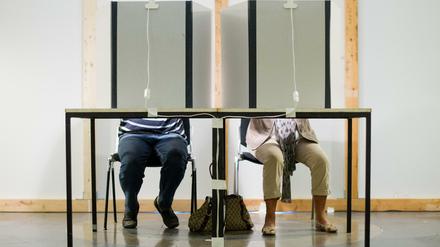 Ein Mann und eine Frau sitzen in einem Wahlraum in Niedersachsen.