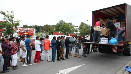Flüchtlinge stehen in Heidenau auf einem Willkommensfest an einem LKW Schlange, um gespendete Sachen entgegenzunehmen. 