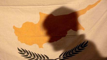 Ein Demonstrant wirft seinen Schatten auf eine zyprische Flagge.
