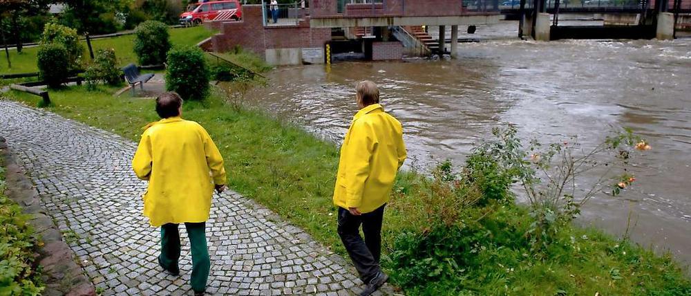 Zwei Deichläufer, die bei Hochwasser den Zustand der Deiche überwachen, gehen am Stadtmühlenwehr in Spremberg an der Spree entlang. 