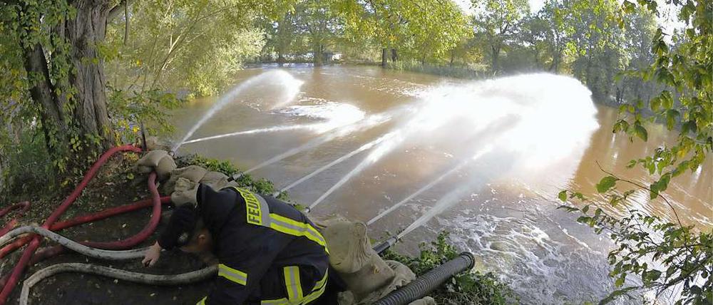 Feuerwehrleute pumpen Wasser von einer überschwemmten Fläche in die Schwarze Elster.