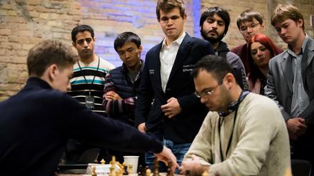 Schachweltmeister Magnus Carlsen (Mitte) beobachtet bei der Blitzschach-Weltmeisterschaft in Berlin eine Schachpartie.