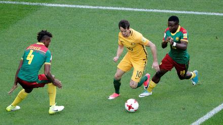 Kameruns Adolphe Teikeu (l) und Collins Fai (r) versuchen Australiens Robbie Kruse den Ball abzunehmen.