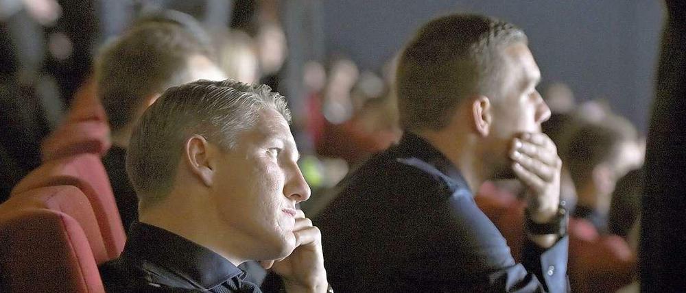 Die Nationalspieler Bastian Schweinsteiger (l.) und Lukas Podolski sitzen bei der Weltpremiere des. Films "Die Mannschaft" im Kino Cinestar im Sony Center am Potsdamer Platz.