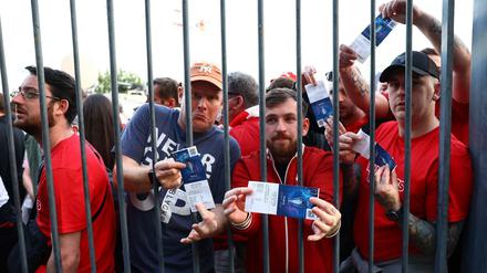 Fans des FC Liverpool warten vor dem Stadion und präsentieren ihre Karten.