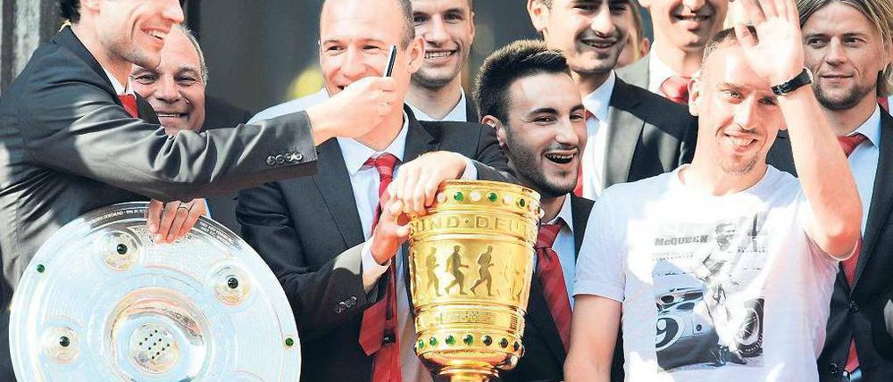 Einer fehlt. Ohne die Champions-League-Trophäe wirken Meisterschale und DFB-Pokal etwas verloren auf dem Rathausbalkon. 