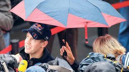 Interviews im Regen. Weltmeister Sebastian Vettel kommt kaum noch zur Ruhe – das gilt auch für viele andere Formel-1-Rennfahrer. Foto: dapd