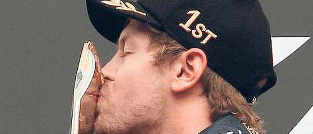 Auf Schmusekurs. Sebastian Vettel kann sich mit der Trophäe für den Sieg in Spa offensichtlich anfreunden. Foto: dapd