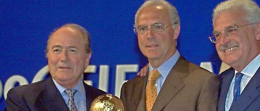 Lächeln süßsauer. Joseph Blatter überreicht Deutschlands Bewerbungschefs Franz Beckenbauer und Fedor Radmann den WM-Pokal. Blatters Favorit für 2006 war Südafrika.