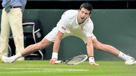 Novak Djokovic steht fast im Spagat auf dem Rasen on Wimbledon.