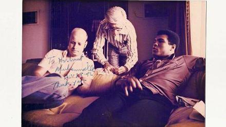 „To Hartmut“. Hartmut Scherzer (l.) sitzt mit Muhammad Ali in dessen Bungalow in Kinshasa. Dick Young von der „New York Post“ ist auch dabei. Später schrieb Ali eine Widmung auf das Foto. Foto: privat