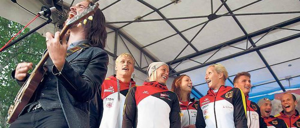 Singen als sportpsychologische Maßnahme. Weltmeister Max Rendschmidt (hinten, ganz links) mit seinen Teamkollegen beim Sommerfest des Deutschen Kanuverbands im Juli, im Vordergrund spielt Gitarrist Simon Goodlife.