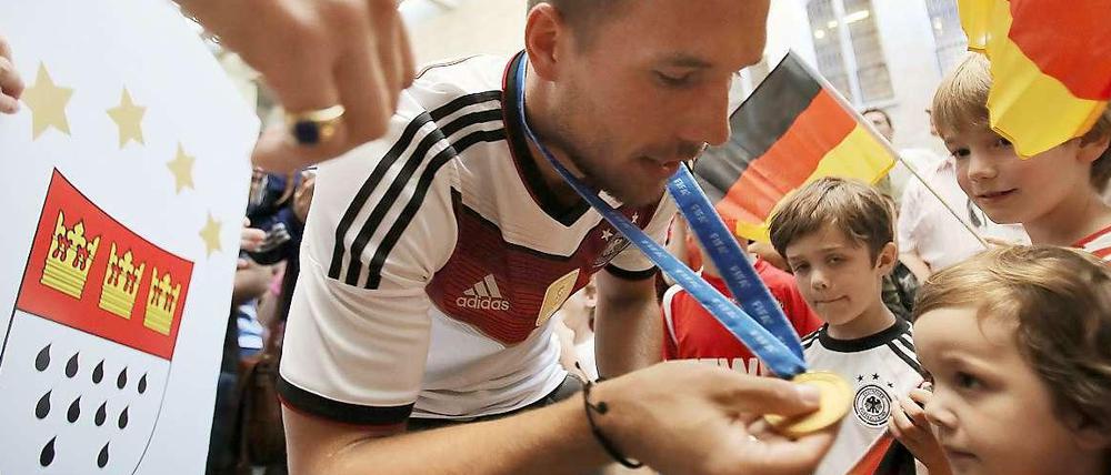 Schau mal her, so sieht ein Weltmeister aus. Lukas Podolski lässt sich nach dem WM-Titel in seiner Heimat Köln feiern.