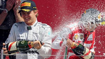 Augen zu und durch: Fernando Alonso (r.) ertrug die Sektdusche von Gewinner Nico Rosberg.