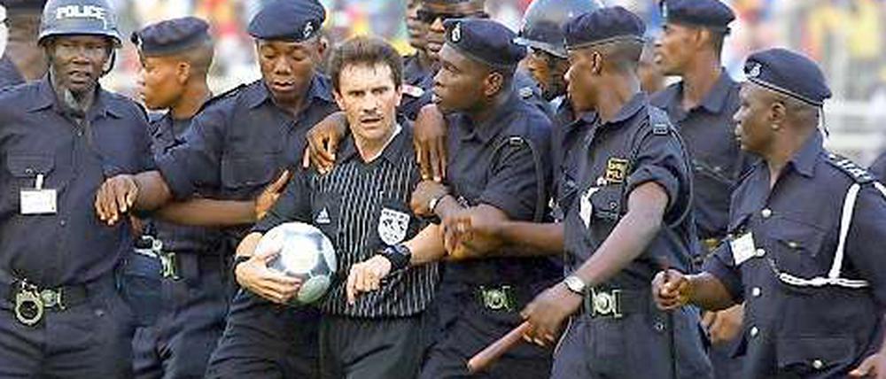 In Sicherheit. Polizisten begleiten den südafrikanischen Schiedsrichter Rubin Williams während des Afrika Cups vom Platz.