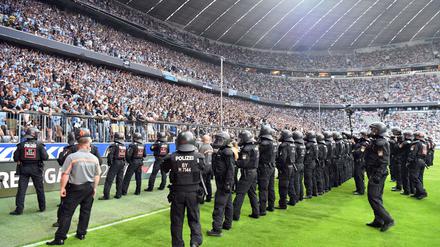Polizisten sichern in der 80. Spielminute das Feld, nachdem Münchner Fans angefangen haben zu randalieren.