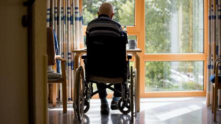 Ein Bewohner sitzt in einem Altenpflegeheim im Rollstuhl in seinem Zimmer.