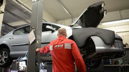 Ein Mitarbeiter der Werkstattkette ATU fährt in der Niederlassung am Frankfurter Ring in München (Bayern) ein Auto auf einer Hebebühne in die Höhe.