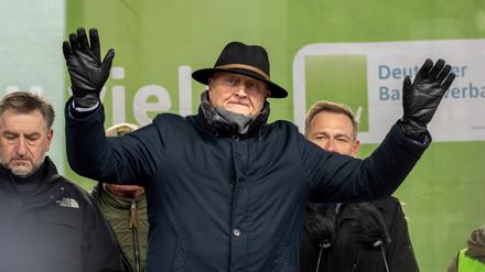Joachim Rukwied, Präsident des Deutschen Bauernverbandes, versucht während der Rede von Christian Lindner (hinten, FDP), Bundesminister für Finanzen, die Landwirte zu beschwichtigen. Die Proteste richten sich gegen geplante Subventionskürzungen durch die Bundesregierung unter anderem beim Agrardiesel. 