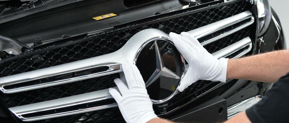 Ein Mitarbeiter von Mercedes-Benz bringt im Werk den Stern an einem Auto der C-Klasse an. 