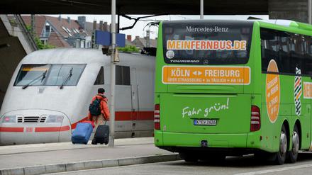 Ein Fernbus steht am im 2013 am Bahnhof in Freiburg (Baden-Württemberg) neben einem ICE-Zug der Deutschen Bahn. Meinfernbus.de gehört mittlerweile zum Marktführer Flixbus.