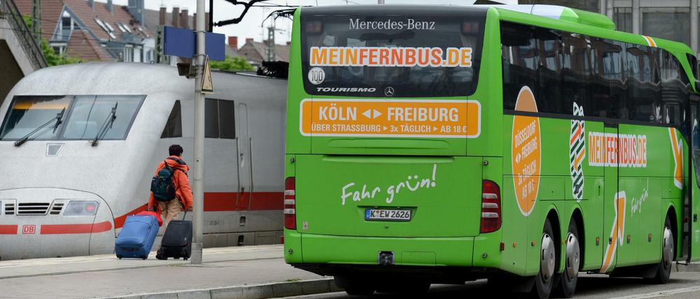 Ein Fernbus steht am im 2013 am Bahnhof in Freiburg (Baden-Württemberg) neben einem ICE-Zug der Deutschen Bahn. Meinfernbus.de gehört mittlerweile zum Marktführer Flixbus.