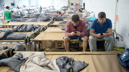 Smartphones sind für Flüchtlinge oft unverzichtbar. Hier chatten die syrischen Flüchtlinge Ammar (l.) und Walid in einer Notunterkunft in der Hanns-Martin-Schleyerhalle in Stuttgart mit ihren Familien. 