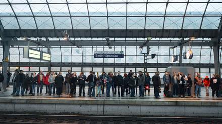 Fahrgäste warten auf einem Bahnsteig des Bahnhofs in Berlin-Spandau auf einen Zug.