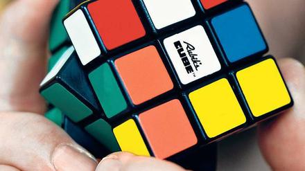 Zauberwürfel. So wird der Rubik’s Cube auch genannt. Aber eigentlich geht es bei dem Spielzeug um Logik. Wer es schafft, die sechs Seiten und 26 bunten Einzelsteinchen so zu drehen, dass die Quadrate auf den Seiten wieder dieselbe Farbe zeigen, hat sein logisches Denkvermögen trainiert. 