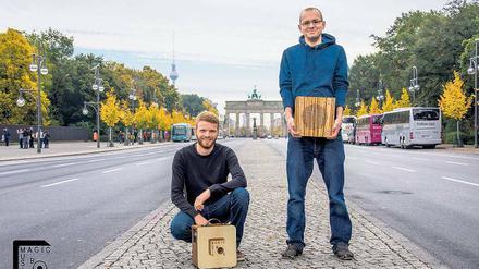 Zwei junge Männer mit Holzkästen vor dem Brandenburger Tor