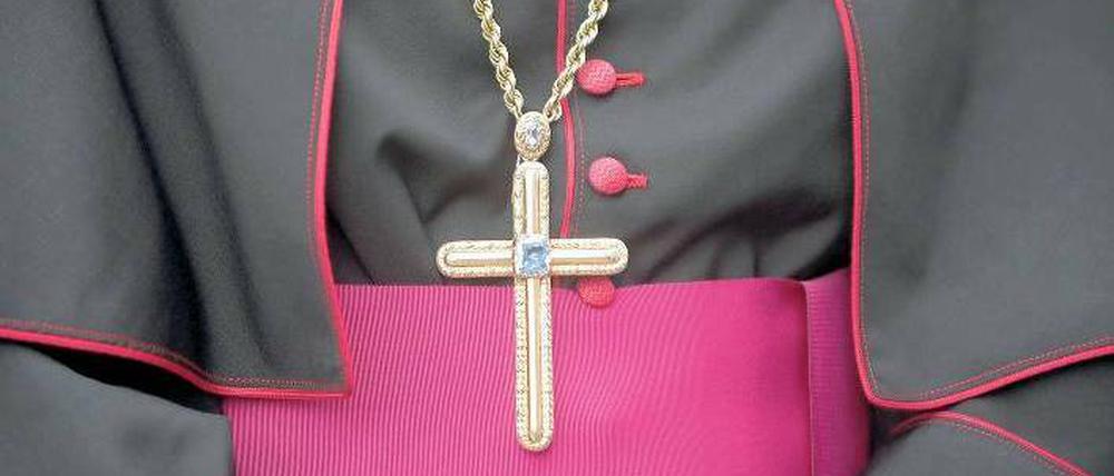 Ein Bischof in seiner Soutane hat ein großes Kreuz an einer Kette um den Hals. 