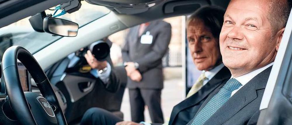 Partner. Olaf Scholz sitzt am Steuer eines Audi, VW-Chef Müller schaut zu.