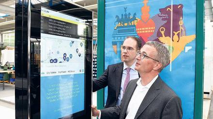  Brandenburgs Wirtschaftsminister Albrecht Gerber (rechts, SPD) lässt sich in der Fabrik des Außenwerbers Wall von Geschäftsführer Patrick Möller eine digitale Anzeige erklären. 