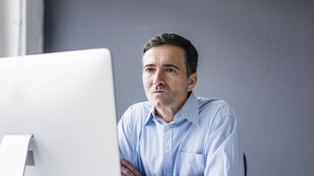 Serious businessman sitting at desk in office looking at computer screen model released Symbolfoto property released PUBLICATIONxINxGERxSUIxAUTxHUNxONLY JOSF02861  