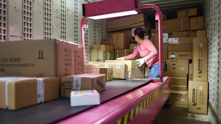 Eine Mitarbeiterin verlädt im Paketzentrum des Logistikkonzerns DHL Pakete in bereitstehende Transportfahrzeuge. 