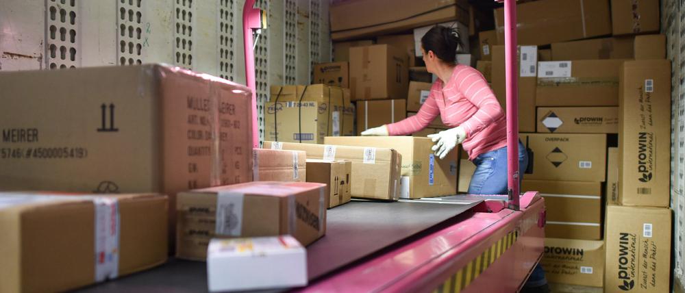 Eine Mitarbeiterin verlädt im Paketzentrum des Logistikkonzerns DHL Pakete in bereitstehende Transportfahrzeuge. 