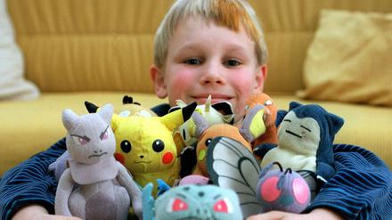 Ein Kind posiert mit seinen Pokemon-Figuren.