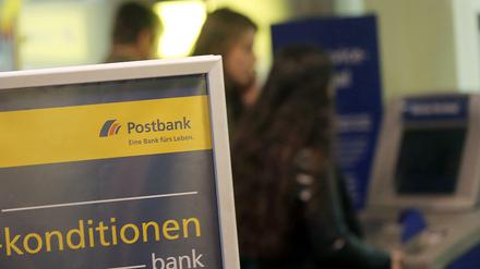 Kunden der Postbank in Köln vor einer Filiale am Geldautomaten. 
