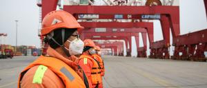 Chinesische Hafenarbeiter tragen Schutzmasken.