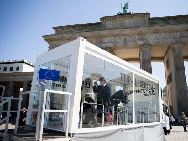 Bürger lesen am Brandenburger Tor in einem gläsernen Leseraum in den von Greenpeace veröffentlichten TTIP-Dokumenten.