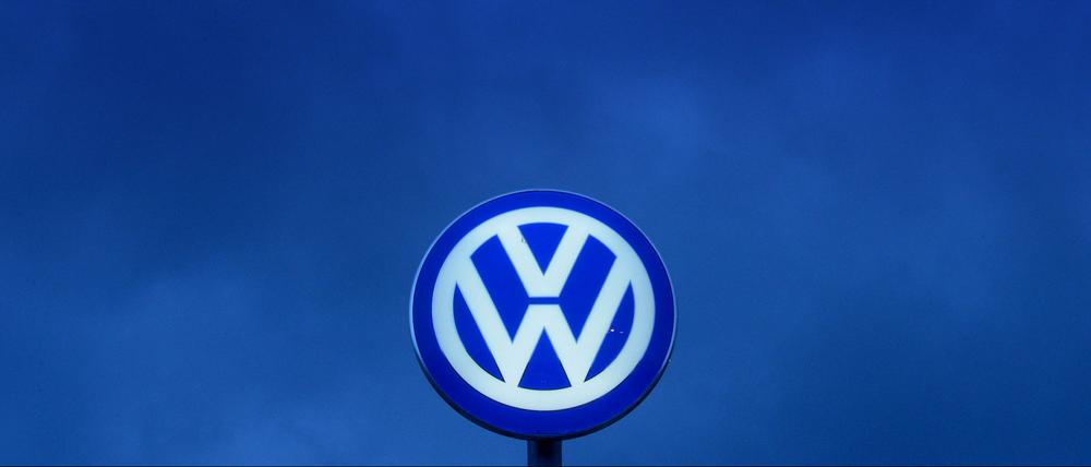 Das VW-Logo leuchtet am Abendhimmel über dem Werkstor von Volkswagen in Wolfsburg.