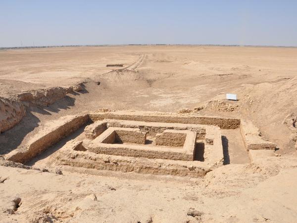 Eine freigelegte archäologische Stätte ist in einer wüstenähnlichen Umgebung zu sehen.