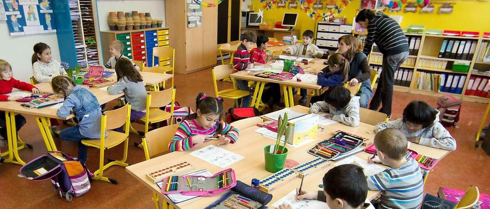 Kinder arbeiten in einem Klassenraum an ihren Tischen.