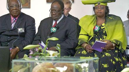 Opfer-Vertreter aus Namibia sitzen bei einer Berliner Trauerfeier im Jahr 2011 vor einem Schaukasten mit Schädeln.