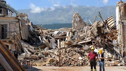 Zwei Feuerwehrleute stehen in den Trümmern der Stadt L'Aquila, die im Frühjahr 2009 von einem Erdbeben getroffen wurde. 