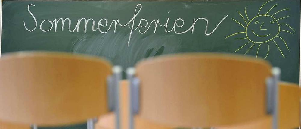 In einem Klassenraum stehen die Stühle auf dem Tisch und auf der Tafel steht "Sommerferien" geschrieben.