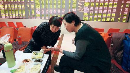 Kleines Geschäft am Rande. Zwei Investoren checken die Kurse am Smartphone in einem Lokal in Shenyang. 