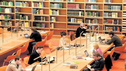 Studenten und Nachwuchswissenschaftler sitzen in der Bibliothek und arbeiten an ihren Laptops.
