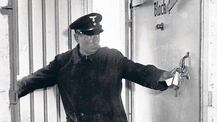 Ein Mann in Uniform öffnet die Tür eines Luftschutzbunkers.